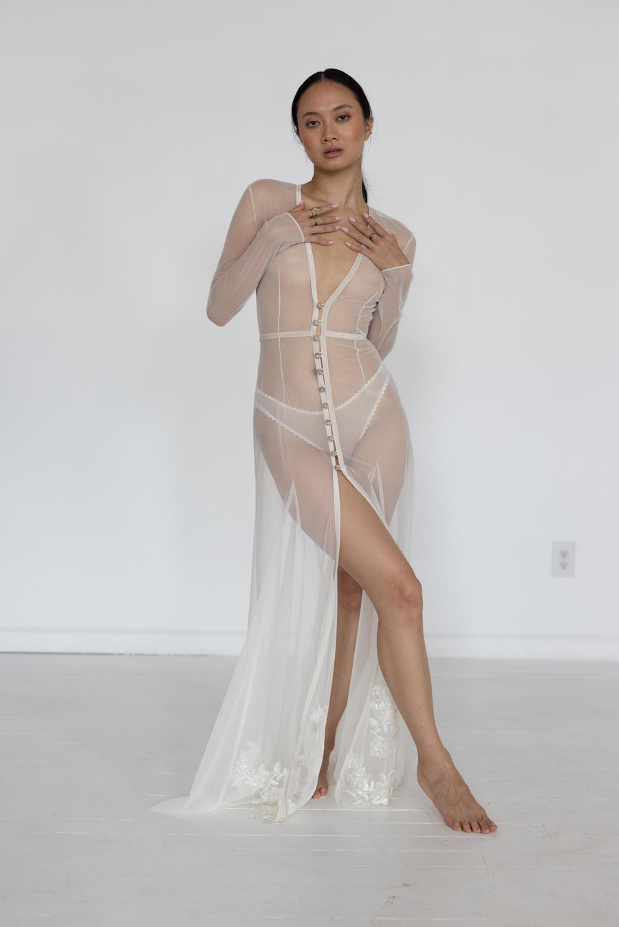 Woman wearing a sheer beige dress with a white background